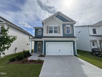 Charming two-story home with a two-car garage, concrete driveway, and manicured lawn at 67 Commons Cir, Clayton, NC 27520
