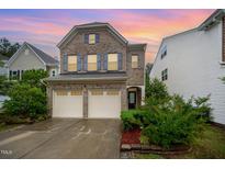 Charming two-story brick home featuring a two-car garage, manicured landscaping, and a welcoming front entrance at 1030 Thoughtful Spot Ln, Durham, NC 27703