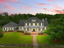 Stately white home with black shutters, columns, and a manicured lawn under a stunning pink and purple sunset sky at 1093 N Lakeside Dr, Smithfield, NC 27577