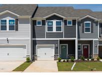 New townhomes featuring attached garages, varied siding, manicured lawn, and inviting colorful front doors at 1167 Abbott St, Mebane, NC 27302