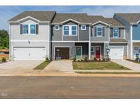 New construction townhomes with single car garages and colorful front doors on a sunny day at 1167 Abbott St, Mebane, NC 27302