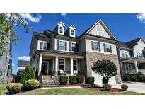 Charming two-story home features a brick facade, covered porch, and beautifully landscaped front yard at 232 Hensley Hill Pl, Holly Springs, NC 27540