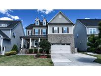 Charming two-story home featuring a welcoming porch, brick accents, and a well-manicured lawn at 232 Hensley Hill Pl, Holly Springs, NC 27540