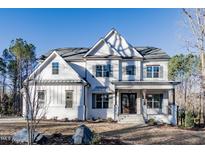 Inviting two-story white home with a charming front porch, manicured lawn, and professional landscaping at 4009 Yates Mill Pond Rd, Raleigh, NC 27606