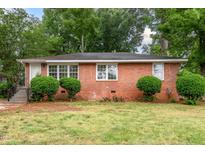 Charming brick home with manicured landscaping, lush trees, and updated windows at 420 Peyton St, Raleigh, NC 27610