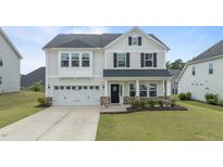 Charming two-story home with a well-manicured lawn, black shutters, and an attached two-car garage at 4718 Sleepy Falls Run, Knightdale, NC 27545