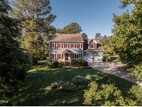 Charming two-story home boasts red shutters, a well-manicured lawn, and mature trees at 5812 N Beaver Ln, Raleigh, NC 27604