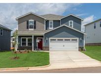 Charming two-story home with a two car garage, landscaped yard, and a welcoming red door at 712 Deschutes Dr, Garner, NC 27529