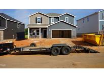 New two-story home featuring gray siding, an open garage, a front porch with space for seating, and unfinished landscaping at 712 Deschutes Dr, Garner, NC 27529