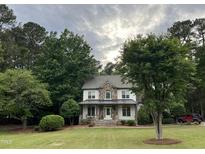 Charming two-story home with a stone and vinyl facade, surrounded by mature trees and lush landscaping at 7501 Tipsy Sq, Wake Forest, NC 27587