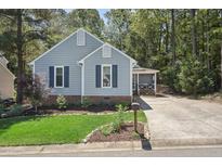 Charming one-story home with blue siding, shutters, a well-maintained lawn and a driveway at 1304 Greenside Dr, Raleigh, NC 27609