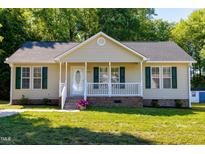 Charming home features a quaint front porch, green shutters, a well-manicured lawn, and an inviting entryway at 1443 Smokey Mountain Dr, Zebulon, NC 27597