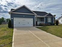 Inviting home with a two-car garage, manicured lawn, and charming front porch at 152 Springtooth Dr, Zebulon, NC 27597