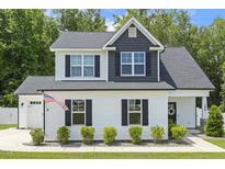 Charming two-story home featuring a white facade, black shutters, and a well-manicured lawn with an American flag at 159 Mitchell Manor Dr, Angier, NC 27501
