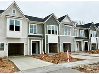 New construction townhomes show attached garages and concrete driveways on an overcast day at 166 Ripple Way # 323, Clayton, NC 27520