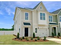 Charming two-story townhome with a one-car garage, black front door, and beautifully landscaped front yard at 174 Ripple Way # 324, Clayton, NC 27520