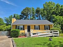 Charming yellow home with well-manicured lawn, accessible ramp, and black shutters at 3612 Satellite Ct, Raleigh, NC 27604