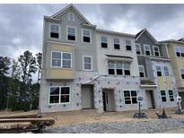 Under construction three-story townhome with large windows and varied facade material with cloudy sky at 376 Chesapeak Commons St # 130, Garner, NC 27529