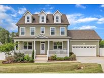 Charming two-story home with a welcoming front porch and beautifully landscaped yard at 384 Grey Hawk Dr, Garner, NC 27529