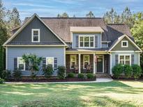 Charming home with blue siding, stone accents, mature landscaping, and a welcoming front porch at 49 Mount Joy Pl, Sanford, NC 27330