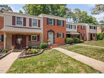 Traditional brick townhomes showcasing well-manicured lawns and charming curb appeal with colorful flowerbeds at 6565 New Market Way, Raleigh, NC 27615