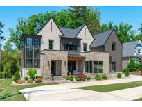 Handsome two-story home featuring brick, stone, and wood accents on a manicured lawn at 702 Wimbleton Dr, Raleigh, NC 27609