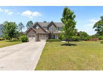 Charming two-story home featuring a stone facade, multi-car garage and a well-manicured lawn at 870 Kentucky Derby Ln, Lillington, NC 27546