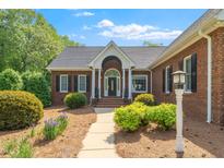 Charming brick home featuring a welcoming front porch and beautifully landscaped yard with mature trees at 8733 Crowder Rd, Raleigh, NC 27603