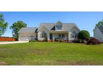 Charming two-story home with a manicured lawn, inviting porch, and attached two car garage at 1009 Open Field Dr, Garner, NC 27529