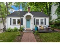 Charming home with a blue front door, brick walkway, and a cozy front porch seating area at 1209 Eva St, Durham, NC 27703