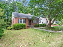 Charming brick home featuring a well-manicured lawn, mature trees, and classic architectural details at 1313 Ridge Rd, Raleigh, NC 27607