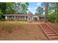 Charming brick home featuring a bay window, manicured lawn, and inviting red brick staircase at 1502 Washington St, Durham, NC 27701
