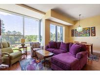 Bright living room with a purple sofa, wooden floors, and golf course views from the large window at 2410 Environ Way, Chapel Hill, NC 27517