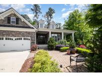 Charming stone home with a two-car garage and an inviting front porch, surrounded by professionally landscaped gardens at 2421 Beckwith Rd, Apex, NC 27523