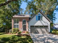 Charming two-story home with brick and siding exterior, manicured lawn, and attached two-car garage at 404 Woodstar Dr, Cary, NC 27513