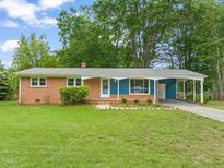Charming single-story brick home featuring a well-maintained lawn, cozy carport, and inviting front porch at 413 Winterlochen Rd, Raleigh, NC 27603
