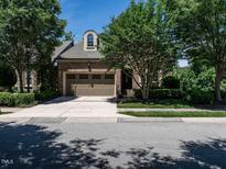 Charming brick home featuring a two-car garage, lush landscaping, and a welcoming curb appeal at 4143 Gardenlake Dr, Raleigh, NC 27612