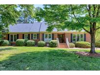 Charming brick home featuring a lush green lawn, mature trees, and classic shutters at 7204 Bellweather N Ct, Raleigh, NC 27615
