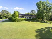 Charming home featuring a well-manicured lawn, mature trees, and a welcoming screened porch perfect for outdoor enjoyment at 9 Lakeview Dr, Sanford, NC 27332
