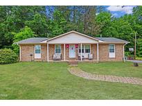 Charming brick home with a well-maintained front yard and inviting entrance with rocking chairs on the porch at 901 Currin Perry Rd, Zebulon, NC 27597