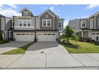 Attractive gray townhouse with two-car garage, a driveway, and well-maintained front lawn at 1011 Canary Pepper Dr, Durham, NC 27713