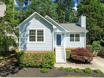 Charming light blue home features mature landscaping, white trim, and a brick foundation at 1040 Mills St, Raleigh, NC 27608