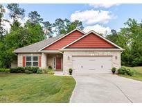 Charming brick home with red accents, manicured lawn and a two-car garage at 11 Woodwater Cir, Lillington, NC 27546