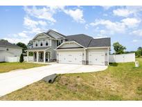 Beautiful two-story home with a manicured lawn, a three-car garage, and a charming stone porch at `120 Red Hawk Pl, Smithfield, NC 27577