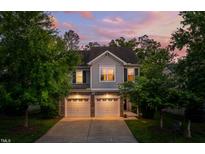 Charming two-story home with gray siding, stone accents, and a two-car garage at dusk at 1908 Woodsdale Dr, Durham, NC 27703
