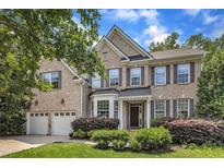 Charming two-story brick home featuring a well-manicured lawn, attached two-car garage, and beautifully landscaped front yard at 205 Forbes Rd, Wake Forest, NC 27587