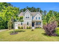 Charming two-story home featuring a well-manicured lawn, stone accents, and a welcoming front porch at 208 Gillean Ln, Holly Springs, NC 27540