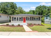Charming single-story home features a red front door, new landscaping, and a concrete sidewalk at 2540 Atlantic St, Durham, NC 27707