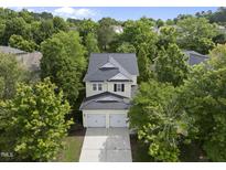 Inviting exterior view of the home showcasing mature trees, a two-car garage, and a meticulously maintained lawn at 3033 Remington Oaks Cir, Cary, NC 27519