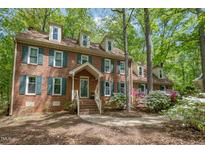 Charming brick home featuring dormer windows, green shutters, and a well-maintained front yard with mature trees at 309 Appaloosa Trl, Bahama, NC 27503